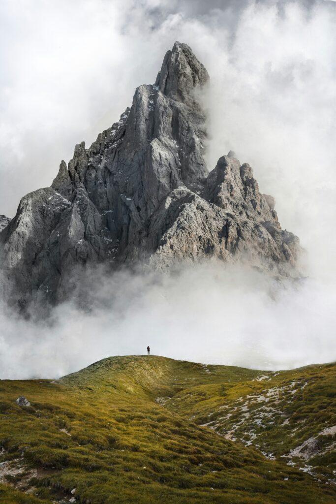 Mensch steht vor einem gewaltigen Bergmassiv